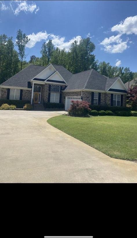 Completed roof on a brick ranch home with a manicured lawn and driveway