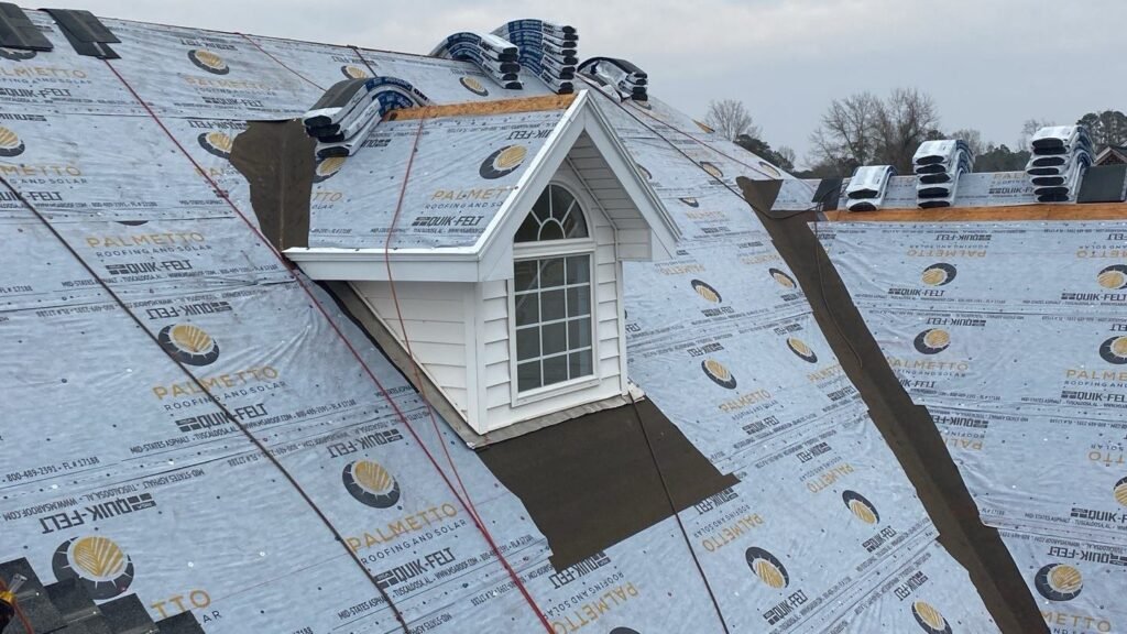 Dormer window surrounded by Palmetto-branded underlayment with ridge vents staged along the roof