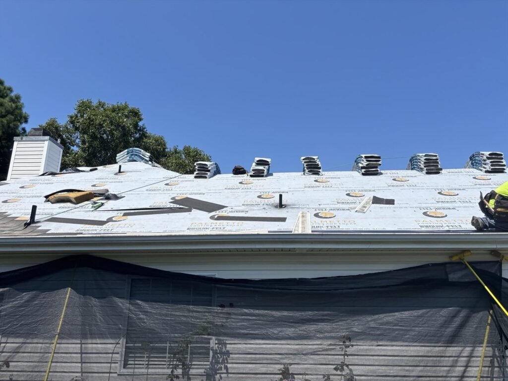 Palmetto branded Quik-Felt underlayment across a roof with shingle bundles and vents staged along the ridge