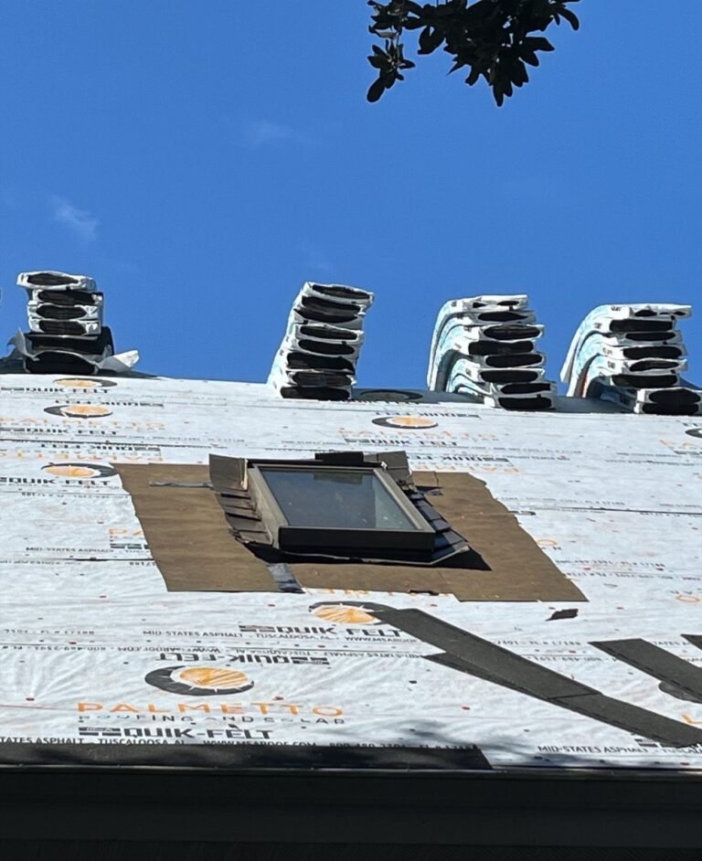 Skylight newly flashed into fresh roofing underlayment with ridge vents staged behind it